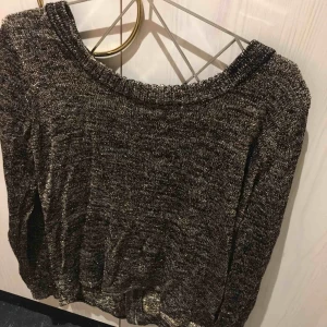  - Snygg, stickad tröja i glitter! Modellen är lite längre och passformen både oversize och tight! Dragkedja bak i ryggen. 