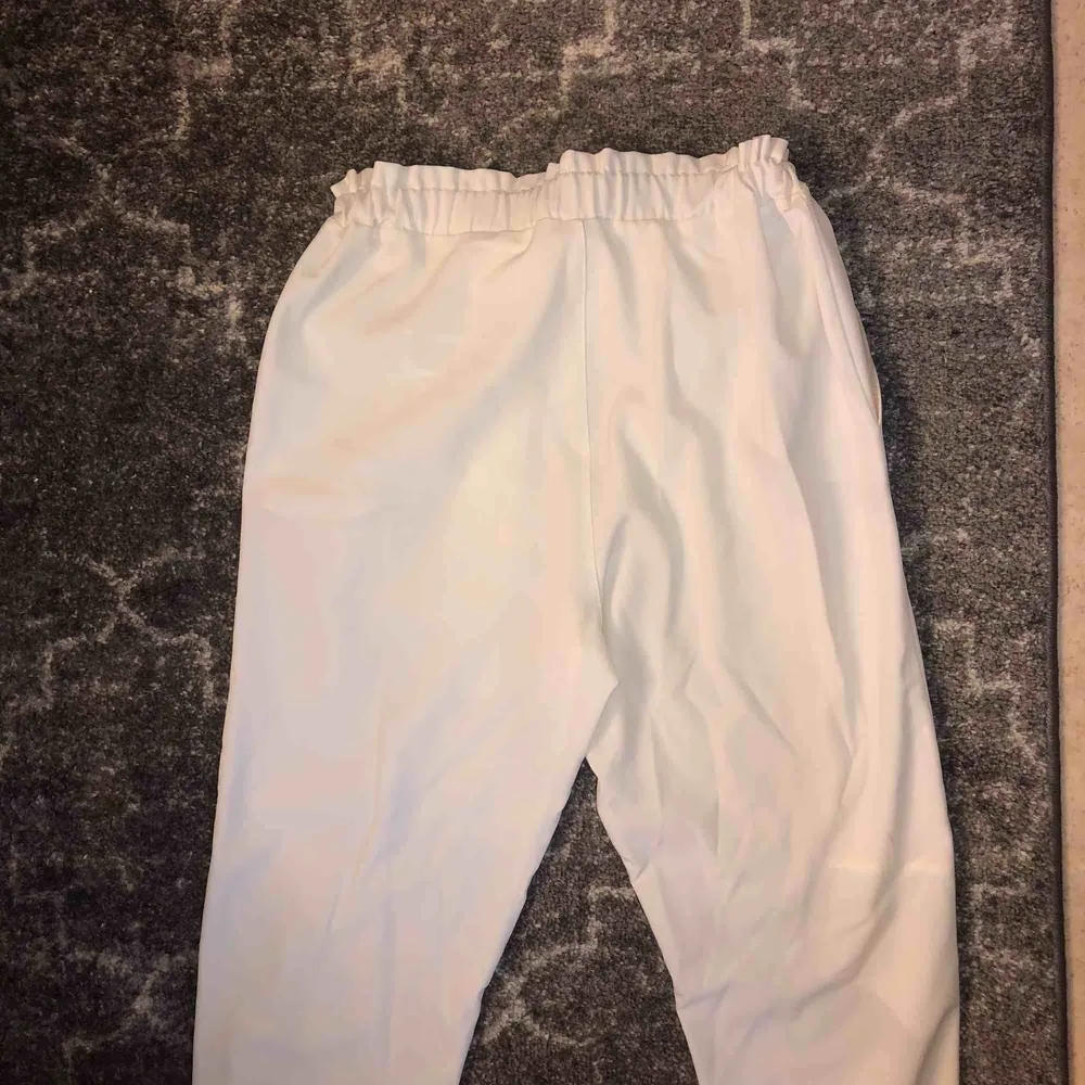 Snygga vita kostymbyxor med resår och knytdetalj! Köpta i år i Spanien, säljes pga för stora . Jeans & Byxor.