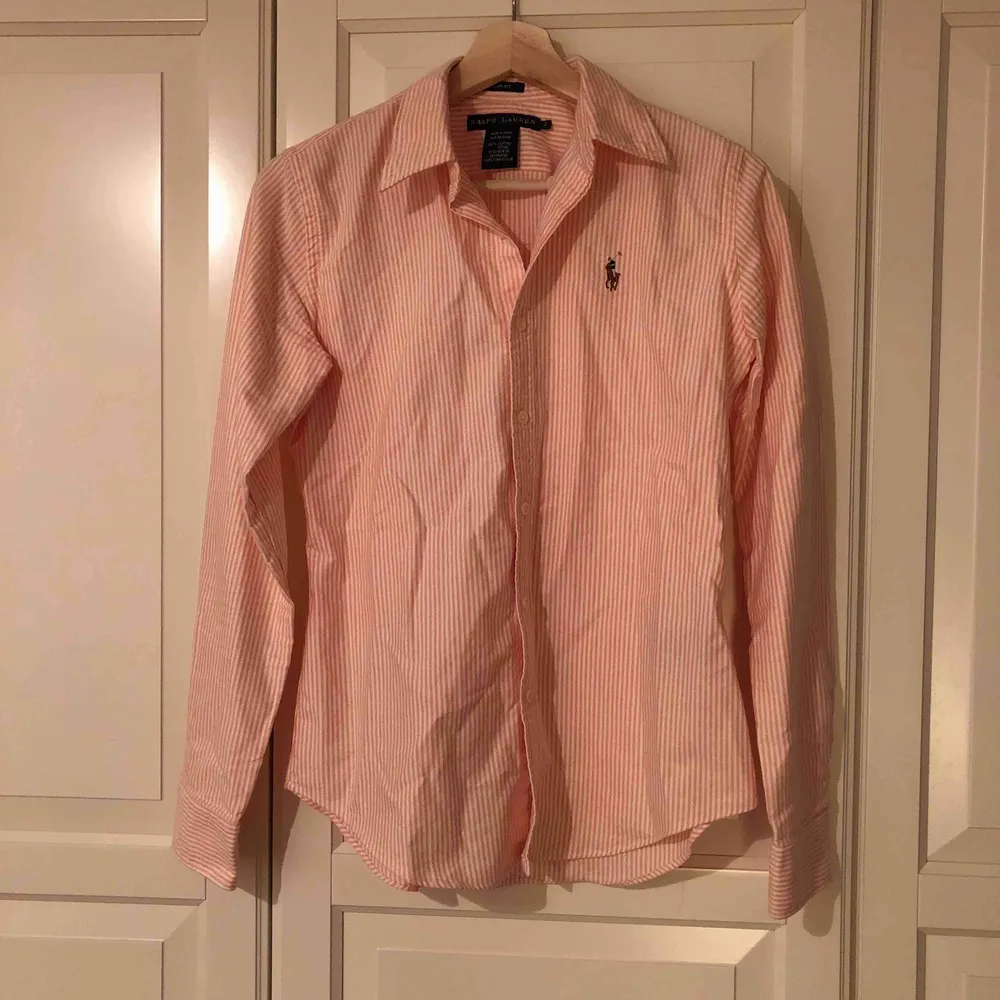 Aprikosfärgad skjorta från Ralph Lauren i USA i storlek 2 vilket motsvarar 34/XS. I fint skick, äkta. Modellen slimfit med ränder. Behöver strykas Hund finns i hemmet. Skjortor.