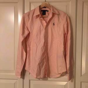 Aprikosfärgad skjorta från Ralph Lauren i USA i storlek 2 vilket motsvarar 34/XS. I fint skick, äkta. Modellen slimfit med ränder. Behöver strykas Hund finns i hemmet