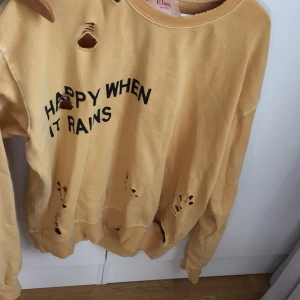  - Supermysig tröja från BIK BOK från Elsa Hosks första kollektion med dem. Lång och mjuk, knappt använd. Det ska vara hål i. Med texten ”HAPPY WHEN IT RAINS”
