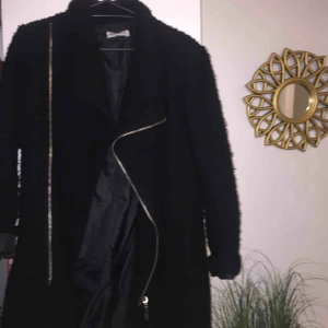  - Svart kappa med en dragkedja på snett. Har en krage och är i storlek small Frakt 40kr