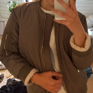  - Grön-brun Bomberjacka med guldiga detaljer. Jacka är inköpt för något år sedan, sparsamt använd.   Finns att hämta i Stockholm alternativt fraktas mot en fraktkostnad. Från ett djur och rök-fritt hem. 