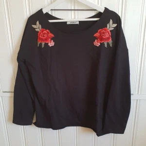  - Snygg svart tröja med broderier på var sin sida. En aning större "urringning" än vanlig tröja men ändå inte offshoulder. Står L i tröjan men skulle säga att den är som en M! 40kr+frakt