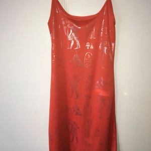  - Kort, orange slip dress med silvrigt tryck på fram och- baksida.  Obs! Har behövt höja priset pga många vill ha klänningen