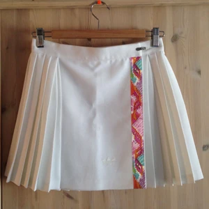  - Vintage tenniskjol från Adidas från 80-talet, tjockt tyg som får fin siluett. Spännes med en slags ”dragkedja” plus kardborrband, så är ganska flexibel i storleken. Den är lite kortare i modellen då det är en sport-kjol. 