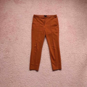  - Low waist ankle kostymbyxor i en fin rost röd/orange färg. Väldigt fint nu i höst! De är använda, och i ok skick.