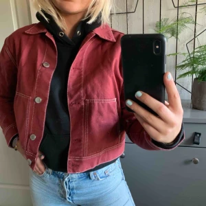  - En röd jacka med vita sömmar som aldrig är använd, det vill säga att jackan i bra skick! 