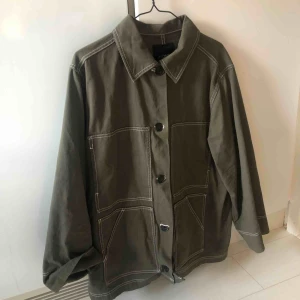  - Snygg grön jacka med vita sömmar. Sparsamt använd. 