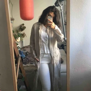  - Tunn beige linnekappa med fickor och skärp. Mycket fin och i bra skick trots skrynklig på bilderna! Köpt second hand men aldrig använd av mig. Från Gina Tricot i storlek S. 