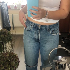 Lågmidjade jeans  - Lågmidjade jeans i storlek M. Byxorna har hål på knäna och har en liten ”slitning” på fickan som jag tycker är as snyggt. 