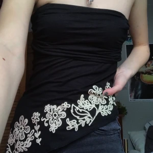 Tubtopp  - Skitfin svart y2k tubtopp med blommönster på och med en sliys på sidan. Köpt second hand. 