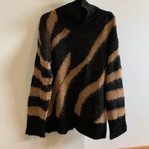 Stickad tröja - Stickad tröja med hög hals. Längre i modellen. I fint skick.