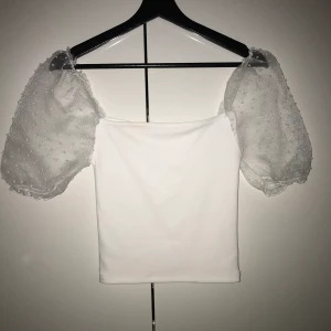 Vit t-shirt med ballong ärm och mesh, XS - Oanvänd, vit t-shirt, med mesh ballong-ärm, ärmarnas material är glansigt, genomskinligt och har små vita prickar, storlek: XS, ifall du möter upp mig så kostar den 50kr, medans om du vill ha den hemskickad så kostar den 40kr eftersom att det medkommer en fraktavgift då💗