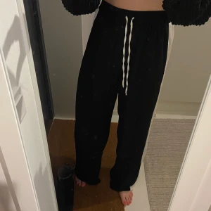 Byxor - Svarta byxor med vit rand på sidorna av benen. Bekvämt, flowigt material. Använda 1 gång. Väldigt skönt och sitter snyggt på kroppen. 