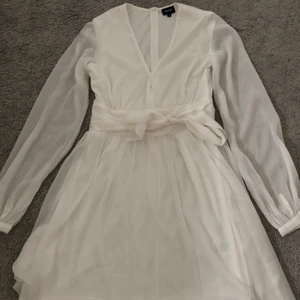 Vit klänning - Säljer denna söta klänning som är använd endast en gång på min skolavslutning för cirka 1 & 1/2 år sen! Superfint med knytning, man kan välja själv om man vill knyta där fram eller bak! Superfint båda två😍 Storlek 36
