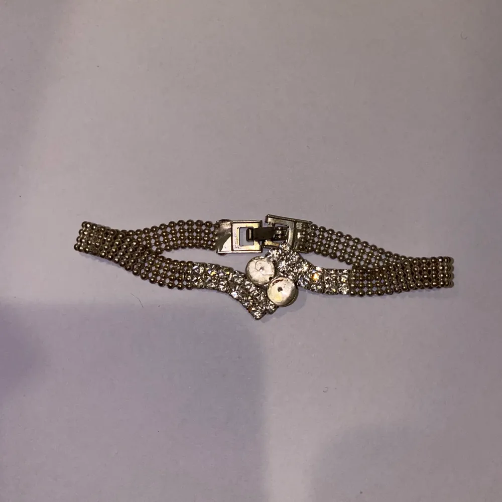 Ett armband som har tappt två ”diamanter” i mitten men den ser fortfarande fin ut. Accessoarer.