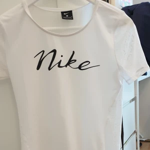 Nike t-shirt  - Vit t-shirt från NIKE. Storlek s men passar alla storlekar beroende på hur man vill att den ska sitta. Materialet där fram är i "träningsmaterial" och baksidan är transparent med små nikemärken. Knappt använd så inga defekter. Skriv för fler bilder🥰