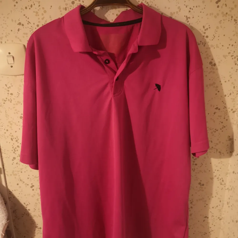 En snygg skrik-rosa polo tröja, köpt på secondhand✨. Det står ej storlek, men skulle säga M-L (herr). Riktigt ball och har ett litet paraply märke🌼. T-shirts.
