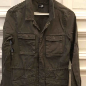  - Cargojacka i mörkgrönt. Dragsko i midjan, tryckknappar.