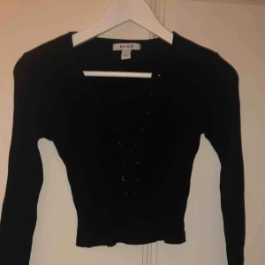  - En svart långärmad croptop från NAKD med snördetaljer. Strl S. Köparen står för frakten