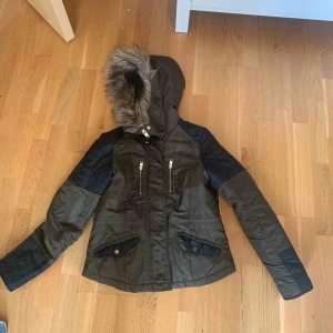  - Grön/svart jacka med pälsluva. Bra skick.