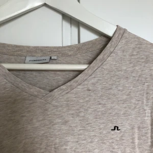 J. Lindeberg T-shirt  - En T-shirt från J.Lindeberg i grå färg med rosa toner. SAMFRAKTAR