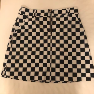 Rutig kjol  - Rutig kjol i svart och vit med en dragkedja framtill, samt hällar för bälte, från Gina Tricot. Sparsamt använd. 