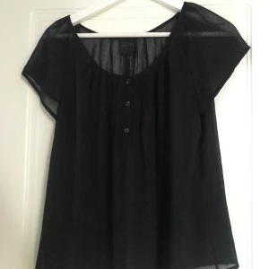 Top - Svart genomskinlig blus, skön på sommaren med ett linne eller bikini under. Strl XS men känns större.