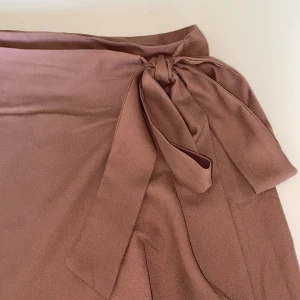 Lång kjol - Lång lila kjol som man knyter omlott i midjan. Jättefin lila färg i fint material, oanvänd. (Har legat nedpackat men blir jättefin när man stryker bort det skryngkliga).  Kampanj: KÖP 3 BETALA FÖR 2