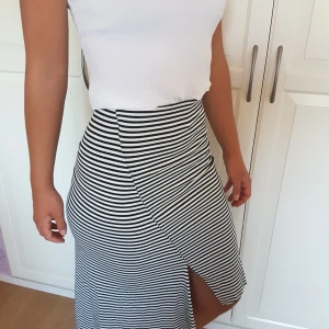 Asymmetrisk randig kjol - Supercool kjol skuren assymetriskt och med liten slits fram. Har resårband i midjan och är väldigt stretching. Frakt ingår!