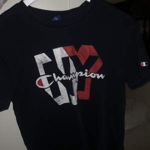 Navy blå (mörk blå) T-shirt från Champion. Köptes från Stadium förra året. Den är inte i dåligt skick utan det är så den var köpt- modellen antar jag ska vara lite ”vintage”.