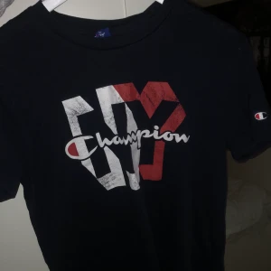 Champion T-Shirt - Navy blå (mörk blå) T-shirt från Champion. Köptes från Stadium förra året. Den är inte i dåligt skick utan det är så den var köpt- modellen antar jag ska vara lite ”vintage”.