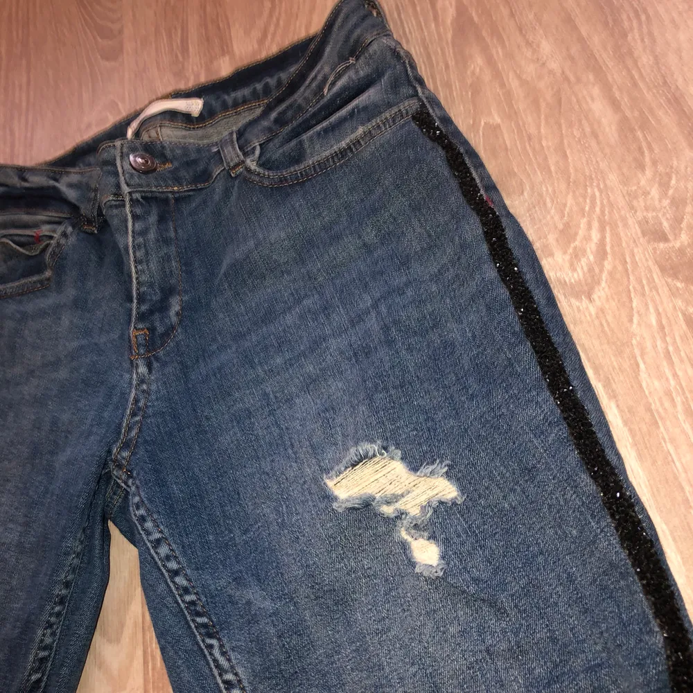 Blåa Zara jeans med slitningsdetaljer och glitterdetalj längst benen. Använda fåtal gånger och i mycket fint skick! Strl 38. . Jeans & Byxor.