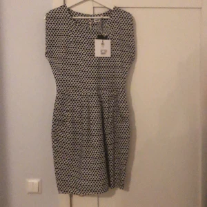 Klänning, Objekt - Oanvänd klänning från Objekt. Holkärm, lite ’ballongstil’ på kjolen. Fina veck och fickor fram. Stl 36, nypris 399:- Liten knapp bak i nacken. Underkjol.