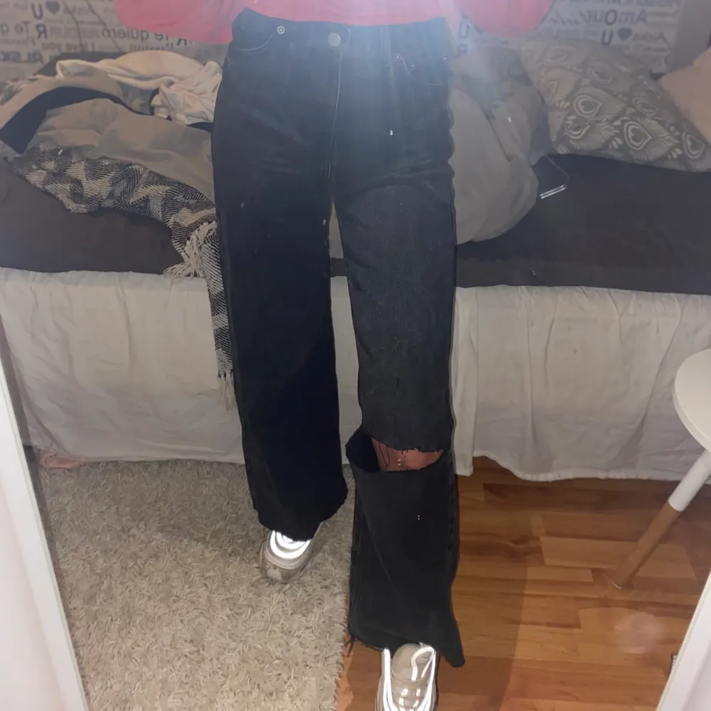 Svarta/mörkgråa jeans i rakmodell samt hål på ett knä. Slitningar längst ner vid benen. . Jeans & Byxor.