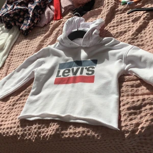 Vit Levis Hoodie  - En vit Levis Hoodie med två linjer i rött och mörk blått. Andvänd ca 3 gånger. Den kostade 600 kr. 