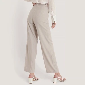 Flared Striped Pants NA-KD - Beigea oanvända kostymbyxor ifrån na-kd str 36. Bilden med modellen är på samma byxor fast i grått ifrån hemsidan. Nypris 500kr *Nyskick, aldrig använda* Denna färgen finns inte kvar att beställa.