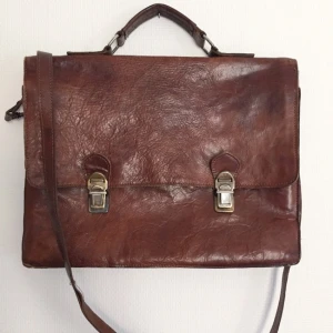  - Den perfekta portfölenj i äkta läder med snyggt slitage. Den är inköpt secondhand men aldrig använd. Kommer ursprungligen från Indiska. Helt felfri med många olika fack samt axelrem. 29 cm på höjden, 37 på bredden. Frakten är inräknad i priset!