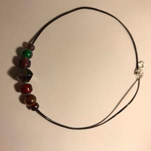 Ett svart halsband med olika pärlor/stenar i olika färger:))