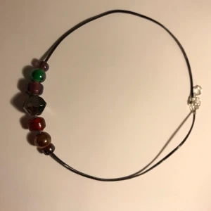 Svart halsband med pärlor  - Ett svart halsband med olika pärlor/stenar i olika färger:))