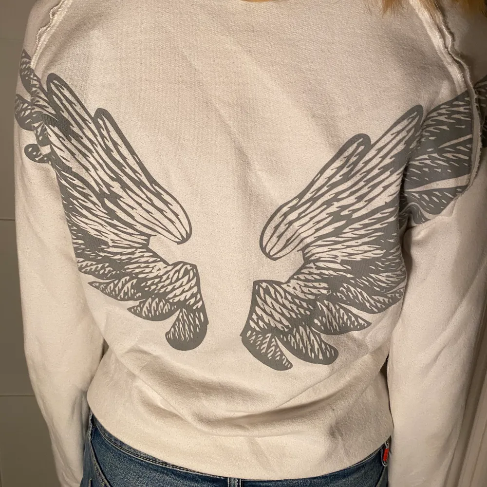 Jättefin vit tröja med gråa vingar på ryggen!Kan möta upp i centrala Stockholm eller frakta men då står köpare för priset för frakten.. Tröjor & Koftor.