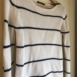 Randig, stickad tröja  - Vit- och blårandig stickad tröja med tre stycken knappar längst ned (baktill). I nyskick, använd endast ett fåtal gånger.