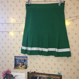 Grön tenniskjol från beyond retro - Grön tenniskjol från beyond retro med en vit rand längst ned. Skönt och rejält tyg! Skriv om du vill att jag ska mäta den!