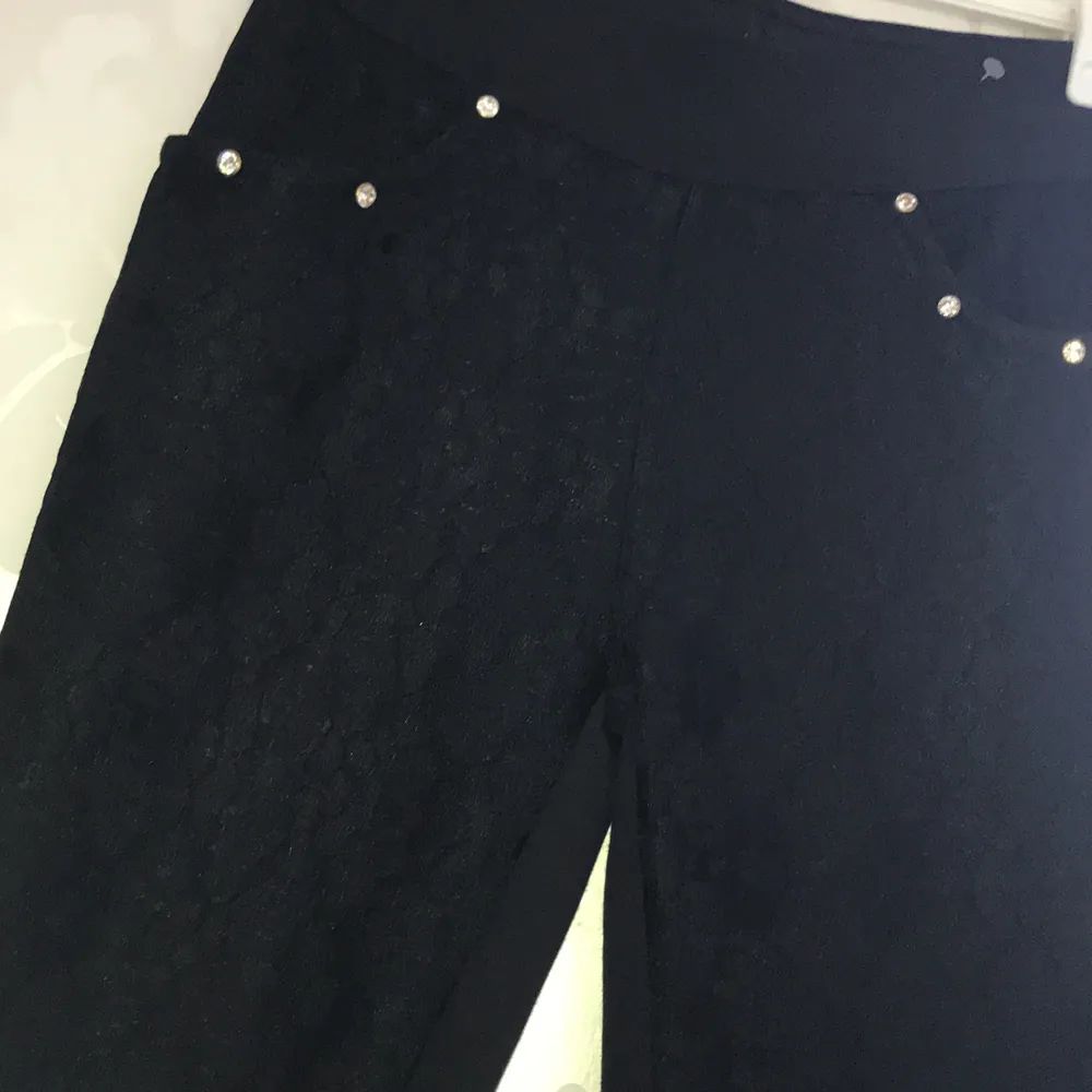 Snygga svarta byxor med blommig mönster fram och diamanter vid fram fickorna i stretchigt material, i storlek S. Jeans & Byxor.