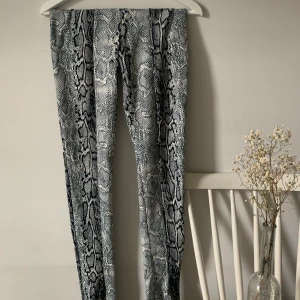 Snakeprint byxor med slits storlek Xs - Byxor i stretch med ormmönster. Slits finns längst ner på framsidan. Skiftar i färger. Knappt använda. Frakt ingår ej 