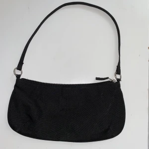 Liten svart axelväska - Trendig axelväska köpt här på plick men inte använd sen dess! Måtten är 27 cm i längd och 13 cm höjd 💗 Frakt tillkommer liten summa om du inte kan mötas i sthlm! 