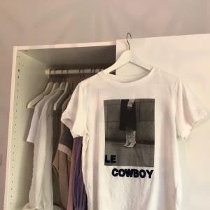 Tröja med tryck - Vit t-shirt med svart vitt tryck, små nitar och text i mörk blå sammet. Som storlek S. 