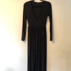 Svart långklänning  - Svart långklänning med långa armar, ganska djup urringning och slitsar vid båda benen. Använd 1 gång. Skickar gärna men köparen betalar frakt 