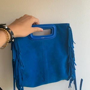 Maje väska  - Säljer min fina Maje väska i en härlig blå färg som piffar upp en outfit, bra skick förutom en fläck från en penna på bild nummer 2 men annars bra skick. Köpt i höstas 2019 på nk. 